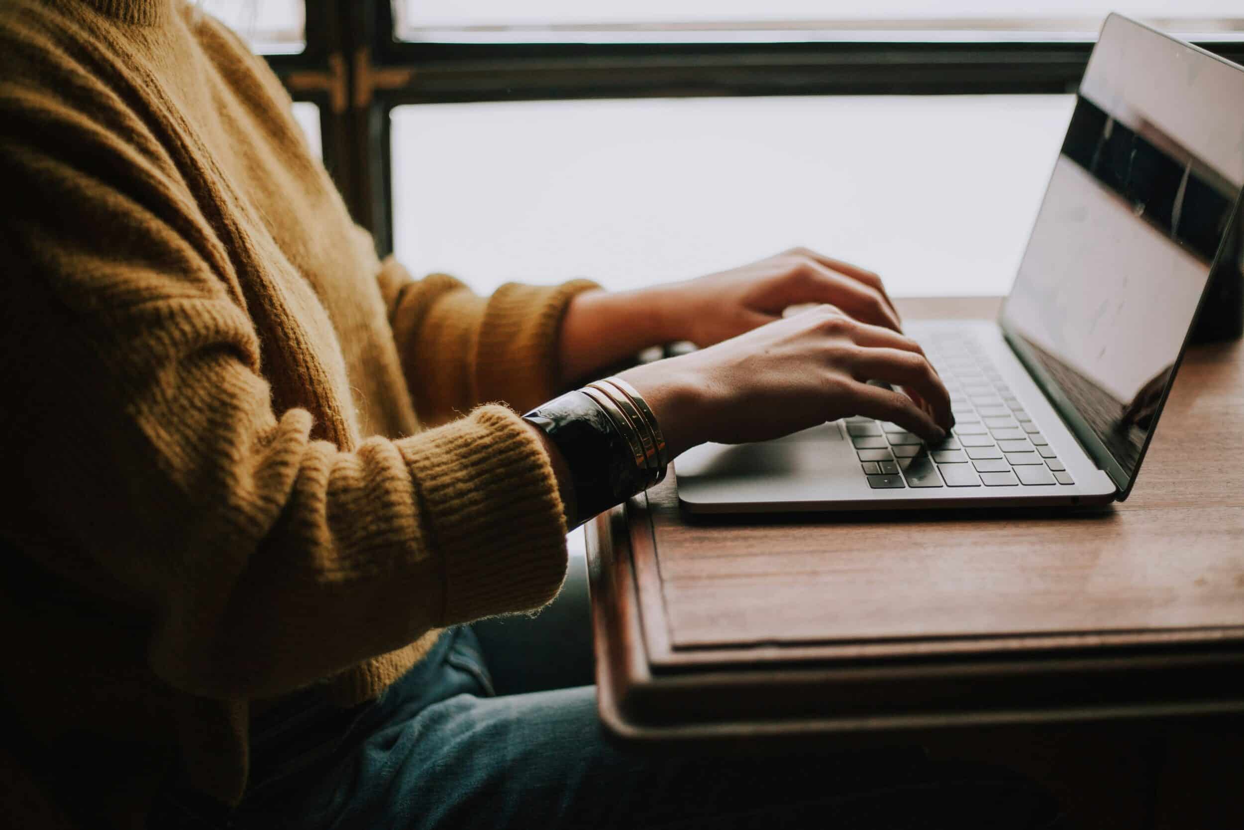 Person typing on computer sitting at a desk.